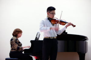 A man playing violin while another plays piano.
