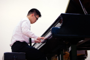 A man playing the piano in front of a white wall.
