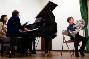 A boy and woman playing piano in an empty room.