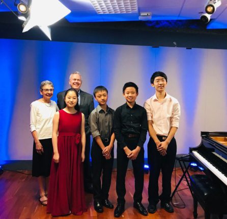 A group of people standing in front of a piano.