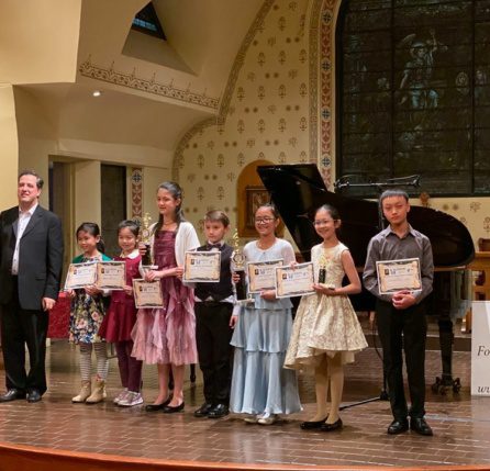 A group of people standing on stage holding certificates.