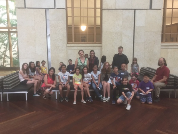 A group of people sitting in front of a wall.