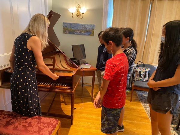 A group of people standing around a piano.