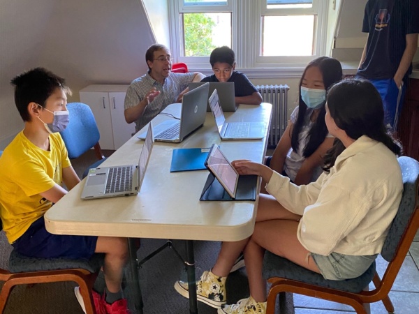 A group of people sitting at a table with laptops.