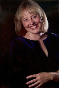 A woman smiling for the camera in front of a black background.